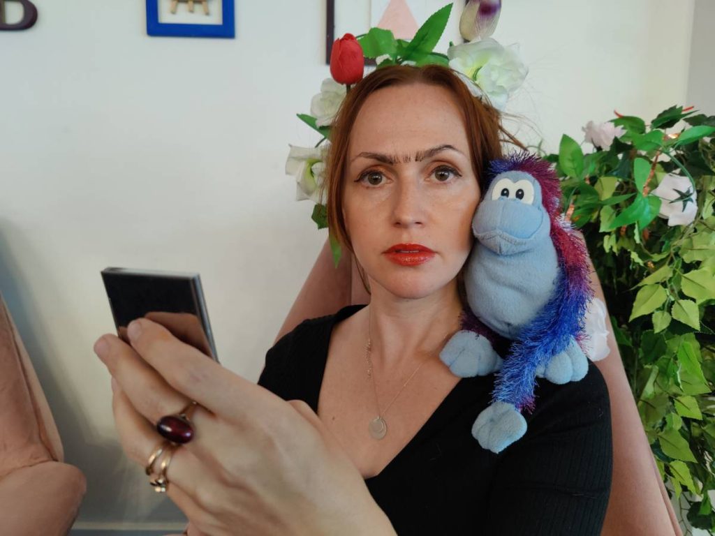 a woman holding a toy on her shoulder dressed as Frida Khalo