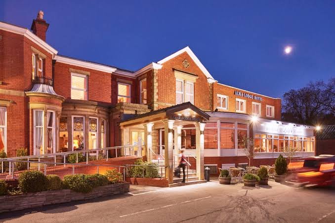 a building with a person walking in front of it Alma Lodge Hotel