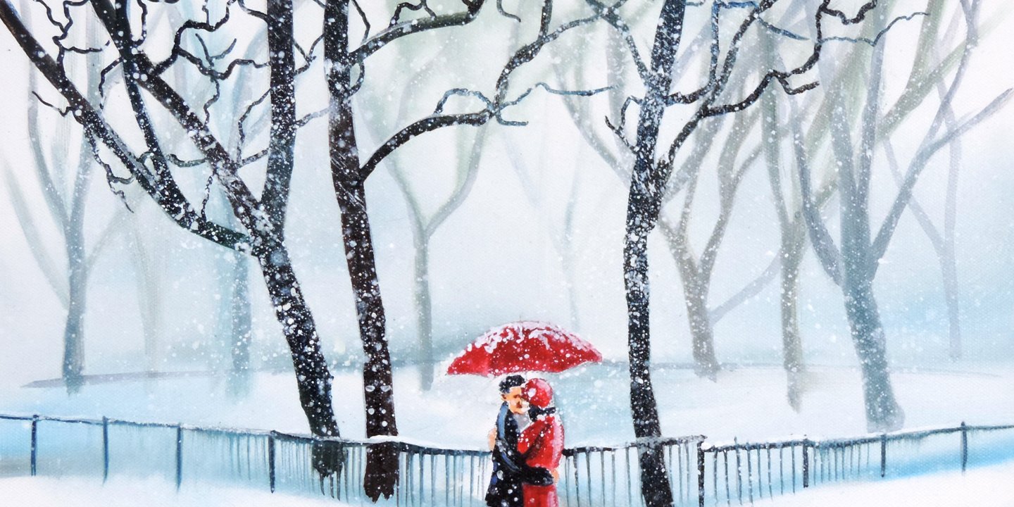 A couple embrace in the snow under a red umbrella
