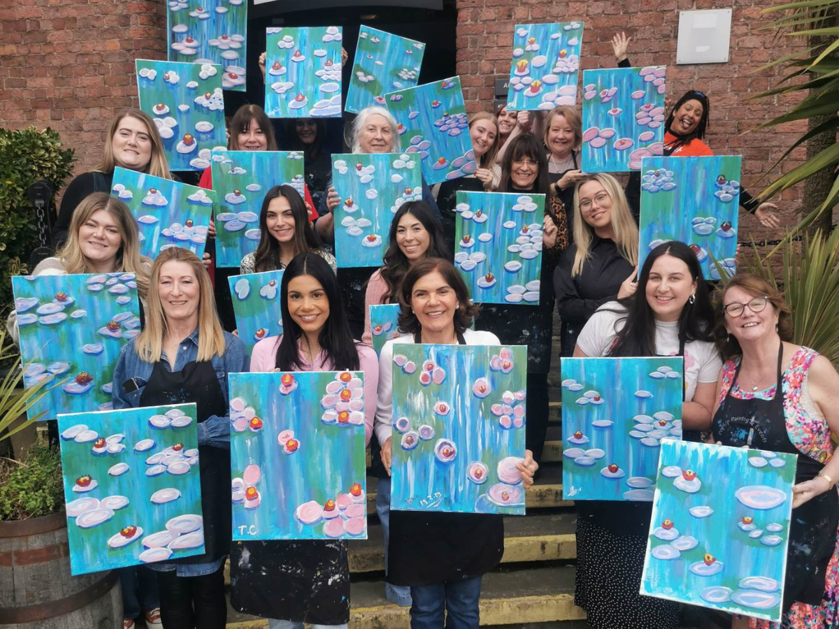 Things to do for Mother's Day - Monet themed sip and paint event! Photo shows a group of people on the steps outside a bar holding up their completed Monet masterpieces based around The Waterlilies